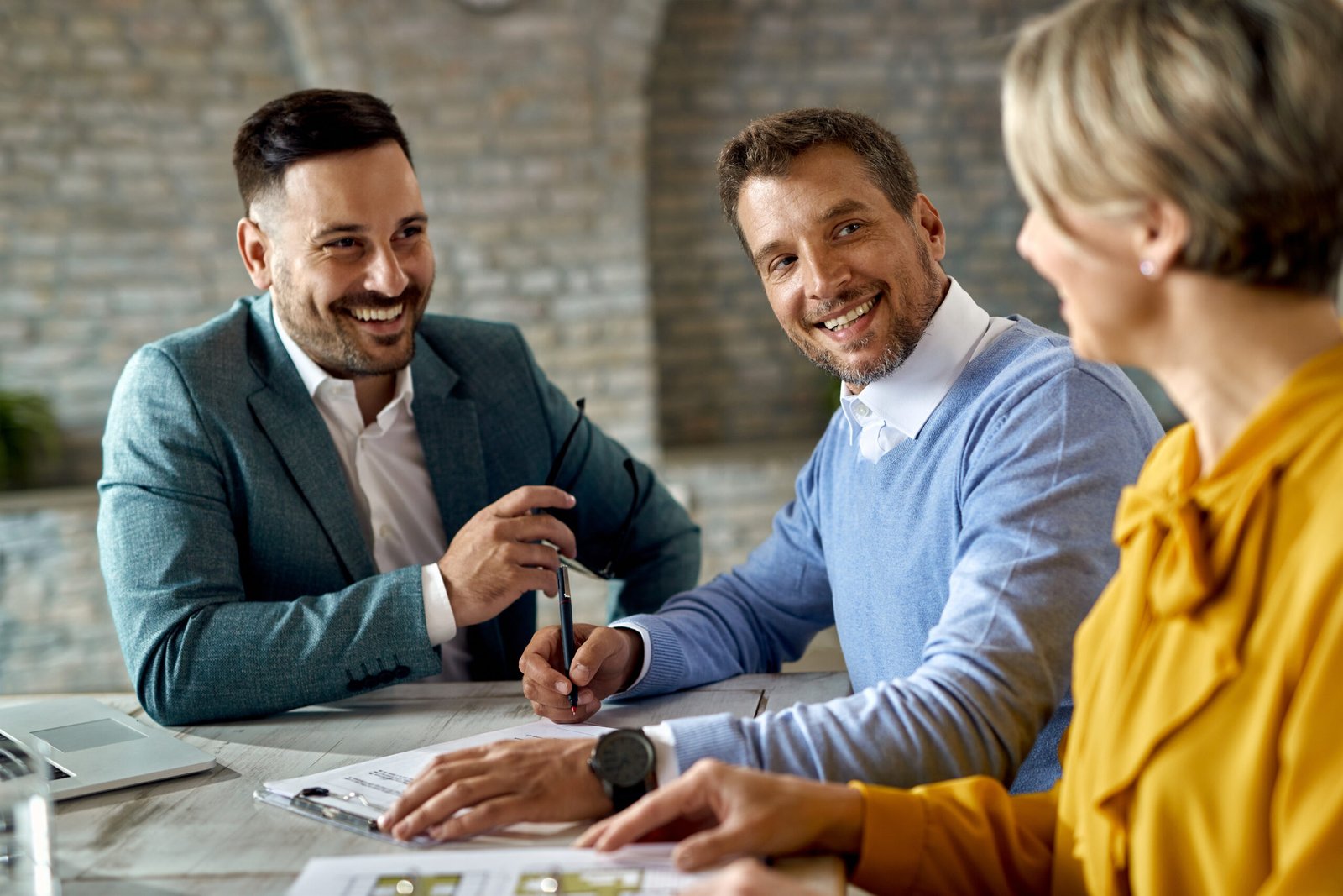 happy man talking his wife while signing agreement with insurance agent office