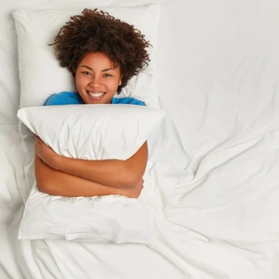 pessoa descansando na cama com travesseiro lencois brancos tecnicas para dormir melhor naturalmente 1